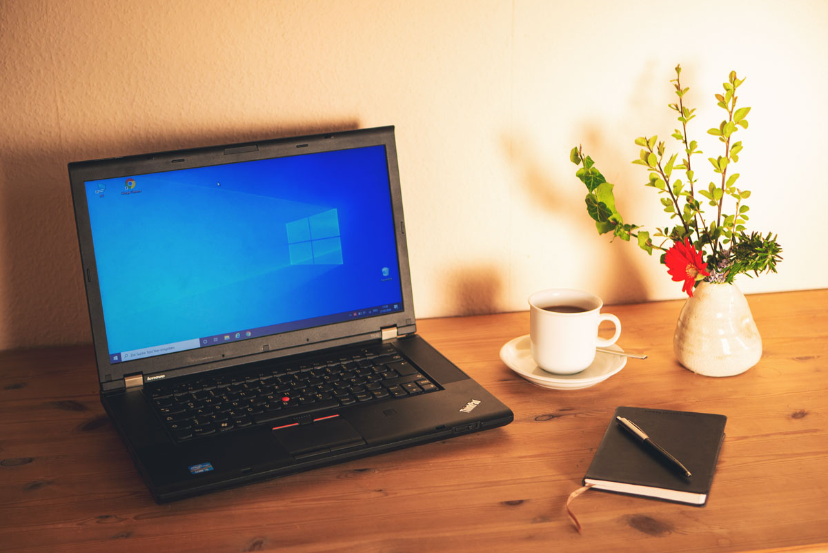 Laptop und Arbeitsmaterialien auf einem Schreibtisch im Homeoffice.